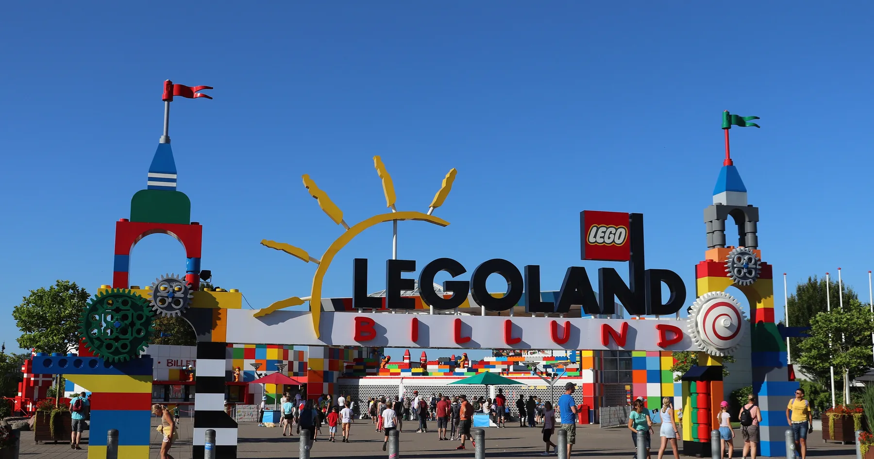 Hovedinngangen til Legoland Billund med LEGO-klosser i portalen og gjester på vei inn